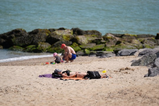 People sunbathe and build sandcastles on a British beach