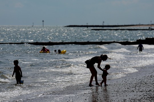 People enjoy sunny weather and play in the sea on a British beach