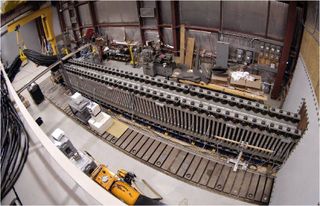 a long metal rail above a row of rectangular magnets in a hangar