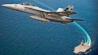 A fighter jet takes off from the surface of an aircraft carrier at sea